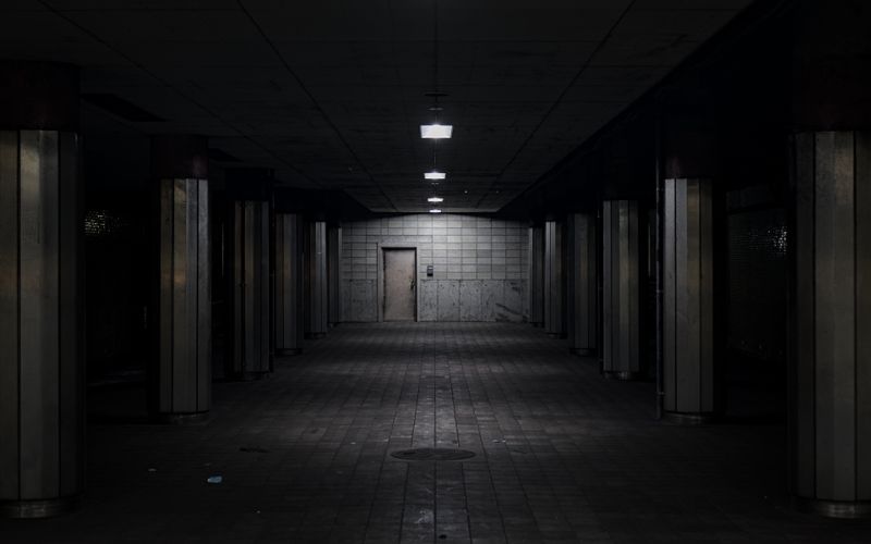 Dimly lit underground corridor with metal pillars